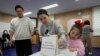 Seorang ibu memberikan suaranya bersama putrinya dalam pemilihan parlemen di sebuah tempat pemungutan suara di Seoul, Korea Selatan, Rabu, 10 April 2024. (Foto: AP)