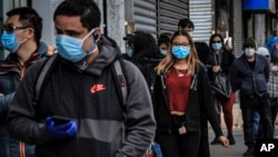 Warga di Sunset Park, di Brooklyin, kawasan yang penghuninya mayoritas orang Meksiko dan Hispanik di di New York, tampak mengenakan masker untuk melindungi dari penularan virus corona, 5 Mei 2020. (Foto: AP)