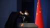 FILE - A worker wearing protective mask against the coronavirus covers the podium after the daily media briefing at the Foreign Ministry in Beijing, China, March 18, 2020. 