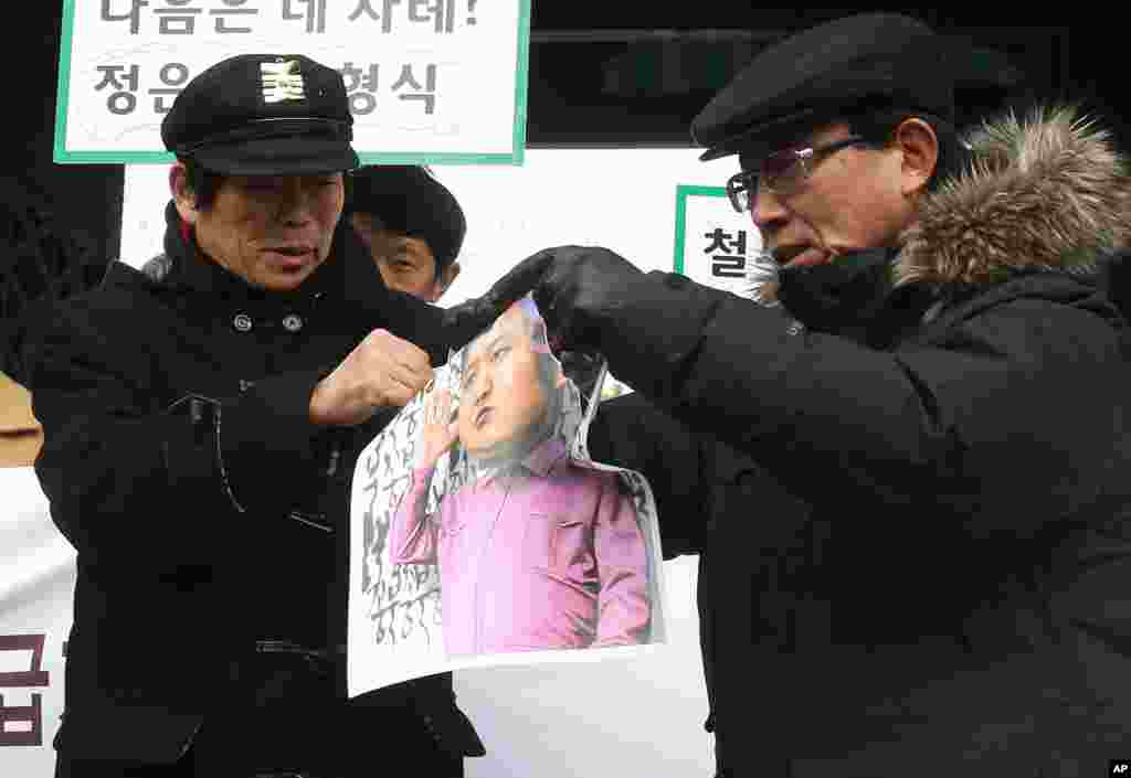 Pembelot dari Korea Utara di Seoul menyobek karikatur pemimpin Korea Utara Kim Jong Un dalam demonstrasi ani-Korea Utara seiring peringatan dua tahun meninggalnya Kim Jong Il (17/12). (AP/Ahn Young-joon)