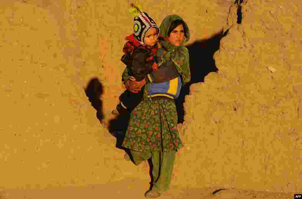 An Afghan refugee holds a child as she stands near her home on the outskirts of Herat.