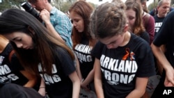 Student survivors from Marjory Stoneman Douglas High School bow their heads as the names of shooting victims are read, at a rally for gun-control reform on the steps of the state Capitol in Tallahassee, Florida., Feb. 21, 2018.