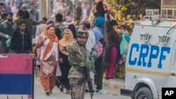 Seorang tentara paramiliter India berjaga sementara yang lain memeriksa lokasi ledakan granat di sebuah pasar di Srinagar, Kashmir yang dikuasai India, Minggu, 3 November 2024. (Foto: AP)