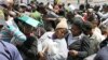 A woman seeks shade beneath her ID documents as she joins about 200 Zimbabweans in a queue outside the Home Affairs offices in downtown Johannesburg, 6 Oct 2010.