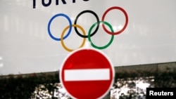 东京街头交通警示牌后的东京奥运会的旗帜。（2020年3月23日）
