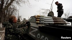 Des miliciens pro-russes chargent le lance-grenades de leur véhicule de combat à Mariupol, en Ukraine, le 12 avril 2022.