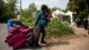 FILE - A pregnant mother who said she was from Haiti and her daughter are watched by Royal Canadian Mounted Police officers as they prepare to cross the U.S.-Canada border into Hemmingford, Quebec, from Champlain, N.Y.
