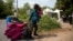FILE - A pregnant mother who said she was from Haiti and her daughter are watched by Royal Canadian Mounted Police officers as they prepare to cross the U.S.-Canada border into Hemmingford, Quebec, from Champlain, N.Y.