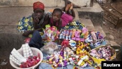  Girls selling sweets watch from their makeshift kiosk - as other boys and girls their age [not pictured] attend school - amid great poverty, in the city of Makeni in Sierra Leone, April 20, 2012.