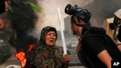 清理抗议营地的埃及安全部队成员跟手持木棍的妇人交谈