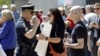 A police officer confronts a woman holding a sign at the North Carolina State Capitol in Raleigh, North Carolina, April 11, 2016.
