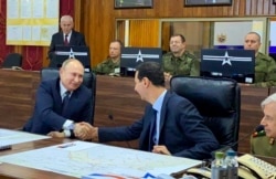 FILE - This image released by the Syrian Presidency shows Russian President Vladimir Putin, left, meeting with Syrian President Bashar Assad, center, in Damascus, Syria, Jan. 7, 2020.