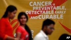 A flash mob participants walk in front of a hoarding spreading awareness on cancer in Hyderabad, India, February 3, 2012. 