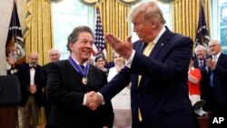 President Donald Trump shakes hands with economist Arthur Laffer after awarding him the Presidential Medal of Freedom, June 19, 2019, in the Oval Office of the White House in Washington.