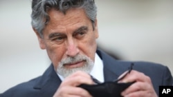 Peru's new interim President Francisco Sagasti takes off his mask after he was designated by Congress to lead the nation, in Lima, Peru, Nov. 16, 2020.