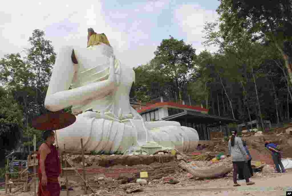 Seorang pendeta Budha dan warga memeriksa patung Buddha yang rusak akibat gempa bumi di kuil Udomwaree di Chiang Rai, Thailand utara. &nbsp;