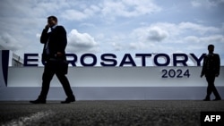 资料照片:2024年6月17日，在巴黎北郊维勒班特，参观者走过欧洲国际防务展(Eurosatory)的标志前。