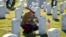 FILE - A female U.S. Marine touches the grave of a friend at Arlington National Cemetery in Virginia.