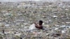A man collects plastic and other recyclable materials from debris in the waters of Manila Bay after tropical storm Saola hit the Philippine capital, July 30, 2012.
