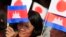 Cambodians hold Japan's flags and their national flags as they listen to Prime Minister Hun Sen's speech during an inauguration ceremony of a road funded by Japan for its official use at Kdey Takoy village, outside of Phnom Penh, Cambodia, Tuesday, March 13, 2018. (AP Photo/Heng Sinith)