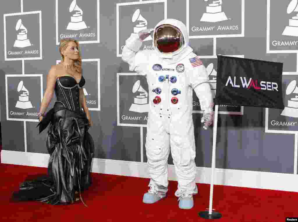 Singer Olga Levit looks on as DJ Al Walser, who is nominated for best dance recording, salutes photographers as they arrive at the 55th annual Grammy Awards in Los Angeles, California February 10, 2013.