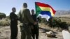 FILE - A member of the Druze community holds a Druze flag as he speaks to an Israeli soldier near the border fence between Syria and the Israeli-occupied Golan Heights, near Majdal Shams, June 18, 2015.