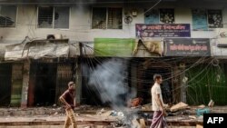 রাঙ্গামাটিতে ২০ সেপ্টেম্বর পাহাড়ি এবং ব্যাঙালিদের মধ্যে দাঙ্গার পর ক্ষতিগ্রস্ত দোকান-পাটের সামনে দিয়ে দু'জন হেঁটে যাচ্ছেন। ফটোঃ ২০ সেপ্টেম্বর, ২০২৪।