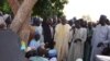 A villager speaks standing next to the governor of Borno State, Kashim Shettima (C), during Shettima's visit to Benisheik, on September 19, 2013, after a violent attack by Boko Haram Islamists kills at least 87 people.