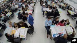 FILE - Workers at the Broward County Supervisor of Elections office, foreground, show Republican and Democrat observers ballots during a hand recount in Lauderhill, Florida, Nov. 16, 2018.