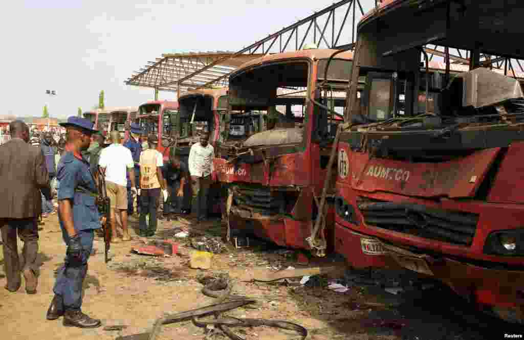 Bomb experts search for evidence in front of buses at a bomb blast scene in Abuja, April 14, 2014.