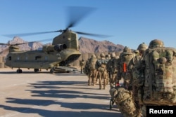 FILE - Soldiers attached to the 101st Resolute Support Sustainment Brigade, Iowa National Guard and 10th Mountain, 2-14 Infantry Battalion load onto a Chinook helicopter to head out on a mission in Afghanistan, Jan. 15, 2019.