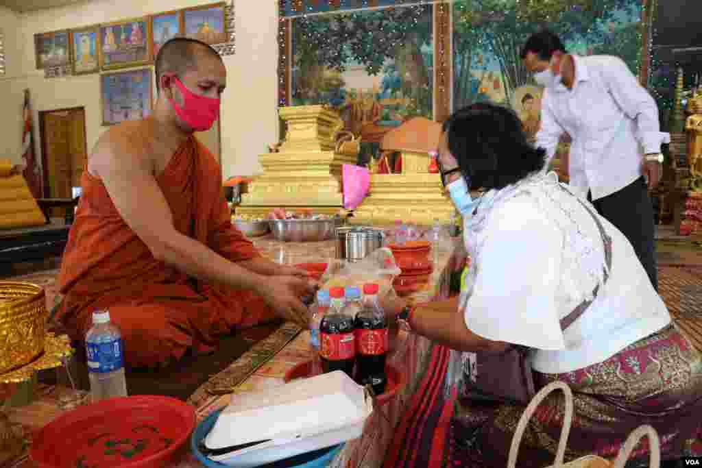 ស្រ្តី​ម្នាក់​កំពុង​ប្រគេន​ទេយ្យទាន​ដល់​ព្រះ​សង្ឃ​​ក្នុង​វត្ត​និរោធ​រង្សី រាជធានី​ភ្នំពេញ ក្នុង​អំឡុង​​ពេល​​ប្រារព្ធ​ពិធី​បុណ្យ​ចូល​ឆ្នាំ​ខ្មែរ​ថ្ងៃទី​២ នៅ​ថ្ងៃ​ទី​១៤ ខែមេសា ឆ្នាំ​២០២០។ (កាន់ វិច្ឆិកា/VOA)​​