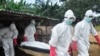 A burial team in protective gear carry the body of a woman suspected to have died from Ebola virus in Monrovia, Liberia. Oct, 18, 2014. 