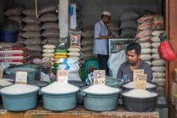 Seorang pedagang beras eceran tengah menunggu pelanggan sambil mengamati telepon genggamnya, di Jakarta, 29 Agustus 2017. (ISMOYO / AFP)