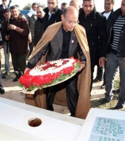 FILE - Then-Tunisian President Moncef Marzouki places flowers Dec.17, 2012, at the tombstone of Mohamed Bouazizi, 26, who set himself alight on Dec. 17, 2010.
