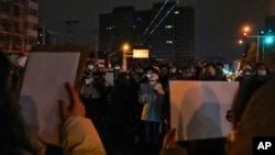 中国多个城市的民众2022年11月27日举起白纸抗议当局严厉的防疫封控措施。（美联社）