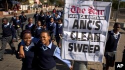 Schoolchildren walk past a newspaper placard reporting the election victory of Jacob Zuma's African National Congress (ANC) party, based on preliminary results, in the Soweto township of Johannesburg, South Africa, May 9, 2014.