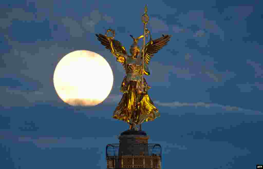 Bulan purnama terlihat di balik tugu kemenangan di kota Berlin, Jerman tanggal 18 Oktober 2013.