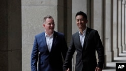 资料照：香港移民官梁镇罡和他的英籍同性婚姻伴侣史葛携手走在香港终审法院外。(2019年6月6日)