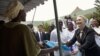U.S. Secretary of State Hillary Clinton (R) gives a mosquito net for malaria prevention to a local woman during a tour of the Philippe Senghor Health Center in Dakar, Senegal, August 1, 2012.