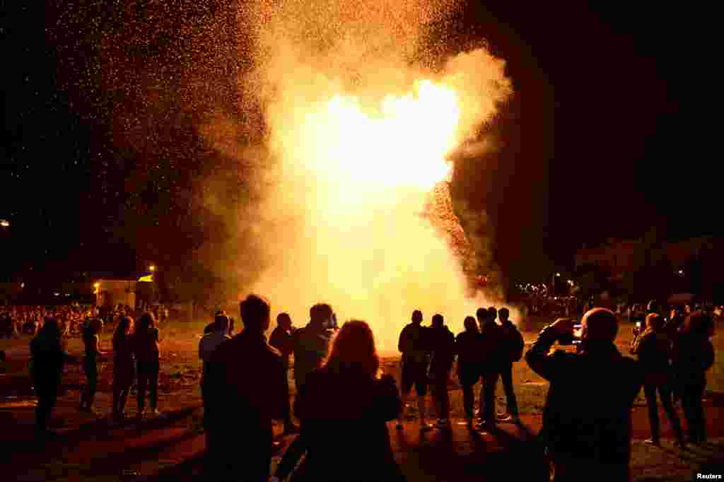 Warga berkumpul di sekitar api unggun menjelang perayaan Hari 12 Juli yang merayakan kemenangan Revolusi Protestan atas Raja Katolik, di Belfast, Irlandia Utara.