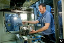 FILE — Brian Gasiewski, who received training at Macomb Community College, removes an external housing for an industrial shock absorber from a CNC machine at Fitzpatrick Manufacturing Co. in Sterling Heights, Michigan.