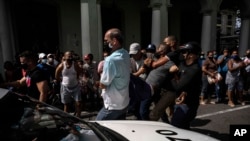 Polisi menahan seorang demonstran anti-pemerintah dalam aksi protes di Havana, Kuba, Minggu 11 Juli 2021. (AP Photo/Ramon Espinosa)