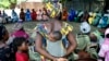 FILE - A mother carrying an infant on her back attends a meeting of women from several communities eradicating female genital mutilation, in Diabougo, Senegal.