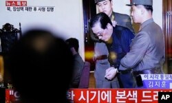 FILE - A man watches a live TV news program showing North Korean leader Kim Jong Un's uncle Jang Song Thaek, second from right, being escorted by military officers during a trial in Pyongyang, North Korea, Dec. 12, 2013.