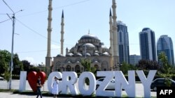 Young people take a photo in front of the Heart of Chechnya - Akhmad Kadyrov Mosque and large letters reading 'I love Grozny' in central Grozny on July 26, 2017. / AFP PHOTO / Kirill KUDRYAVTSEV