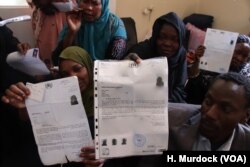 Asylum seekers from Sudan in Libya hold up documents from the United Nations, insisting that they have the right to flee their country.