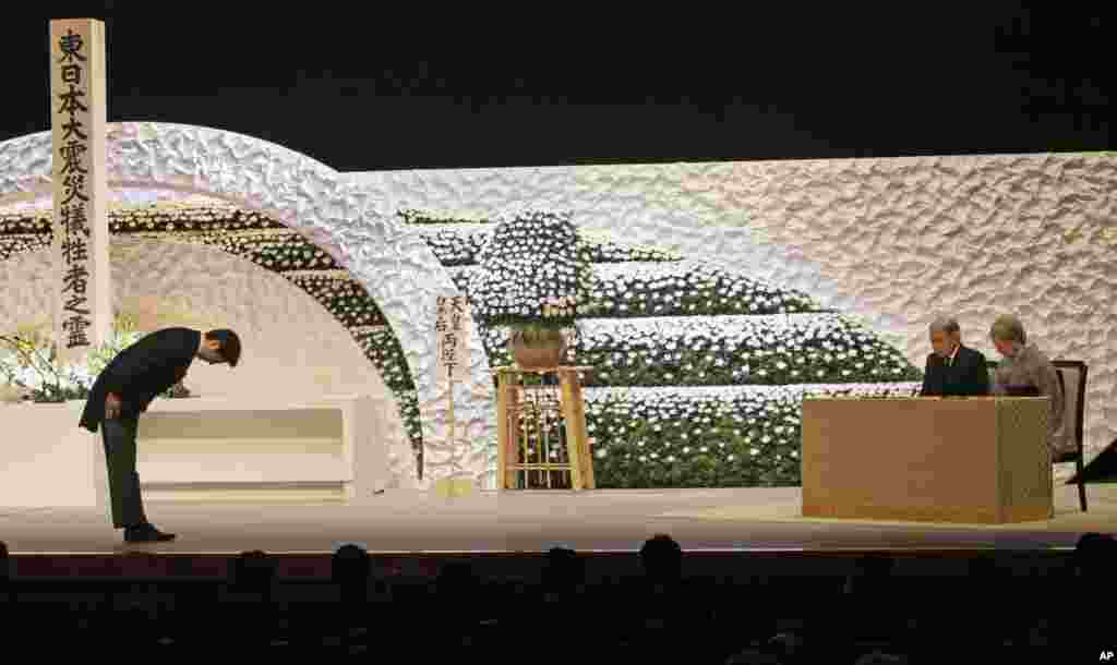 Perdana Menteri Jepang Shinzo Abe memberi penghormatan pada Kaisar Akihito dan permaisurinya Michiko dalam upacara nasional bagi korban tsunami dan gempa bumi (11/3). (AP/Junji Kurokawa)