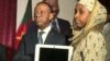 Cameroon's higher education minister, Jacques Fame Ndongo, hands a laptop to a female student, at the University of Yaounde II, in Soa, south of Yaounde, Cameroon, Dec. 27, 2017. (M. Kindzeka/VOA)