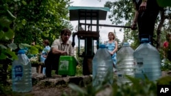 Local citizens line up to collect water, in a street in the center of Slovyansk, eastern Ukraine, July 13, 2014 after pro-Russian insurgents left the city. (AP Photo/Evgeniy Maloletka)